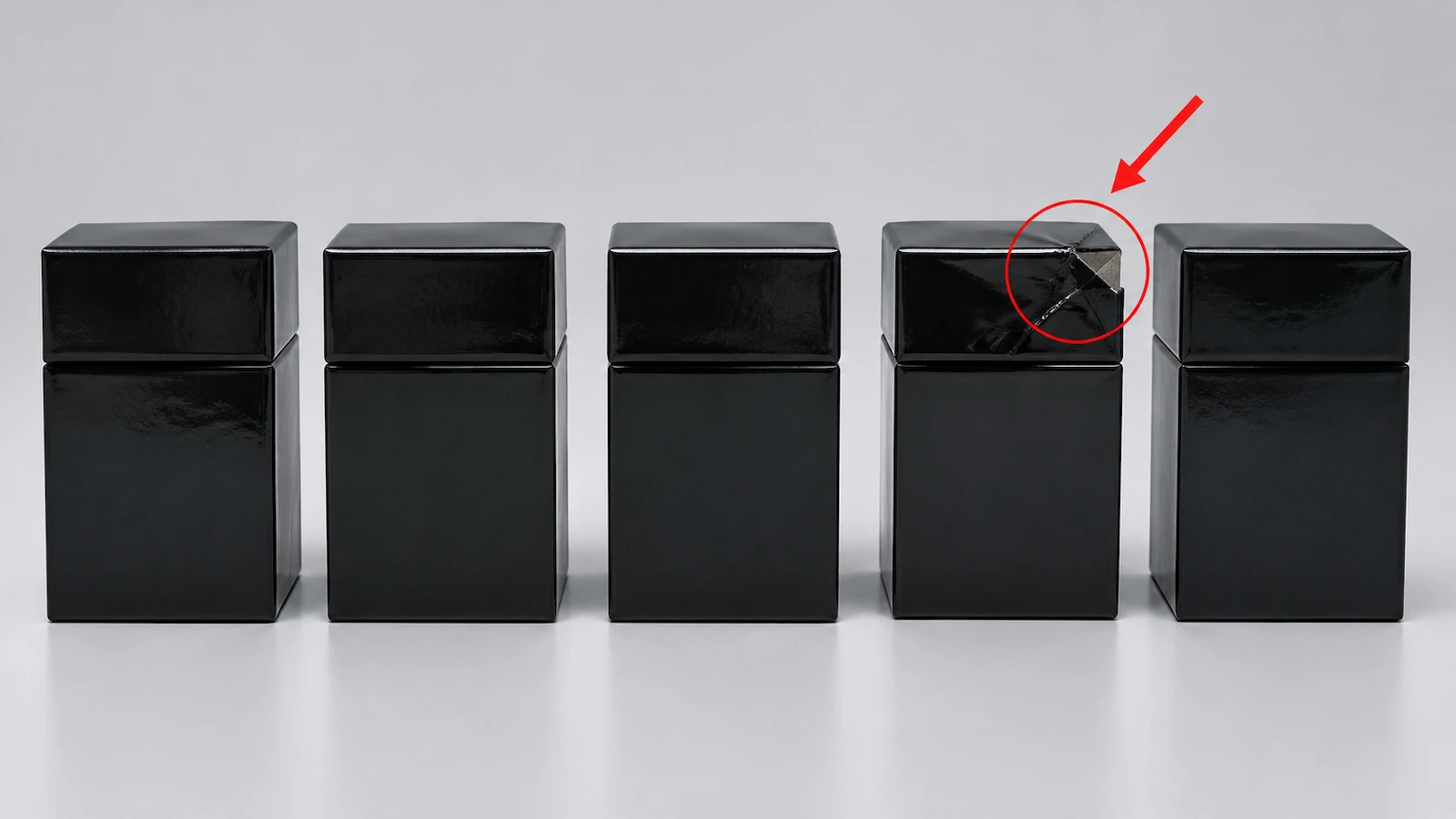 Hàng hộp cứng 2 phần màu đen giống hệt nhau, trong đó một hộp bị móp góc, được khoanh tròn đỏ và có mũi tên chéo đỏ chỉ vào