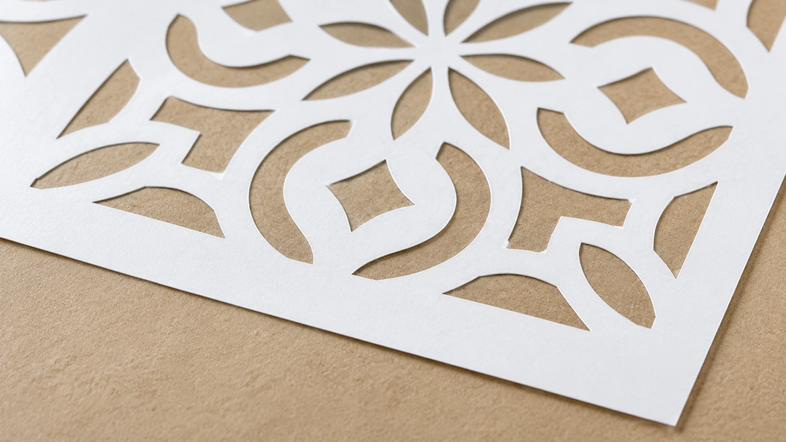 Cận cảnh các hình cắt cong và hình cánh hoa trên stencil màu trắng đặt trên bề mặt màu nâu nhạt